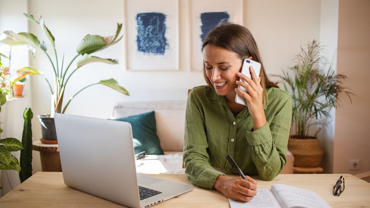 Website%20Dev.%20-%202024-11-04T110257.387 woman in green cardigan on the phone while looking at a computer